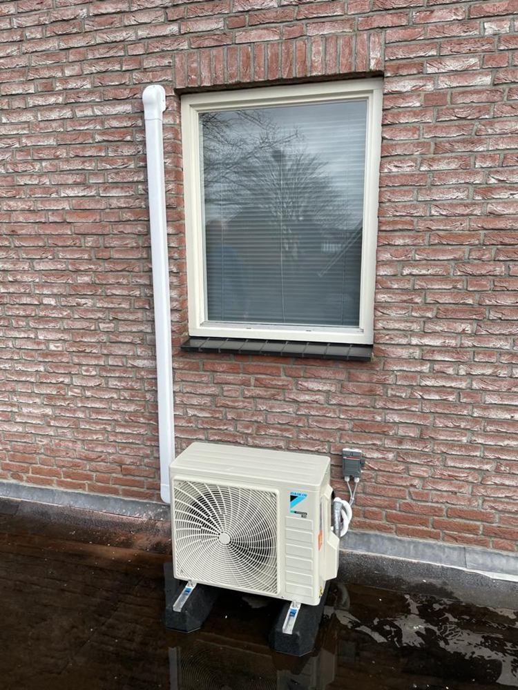 Buitenunit van een airco tegen een bakstenen gevel