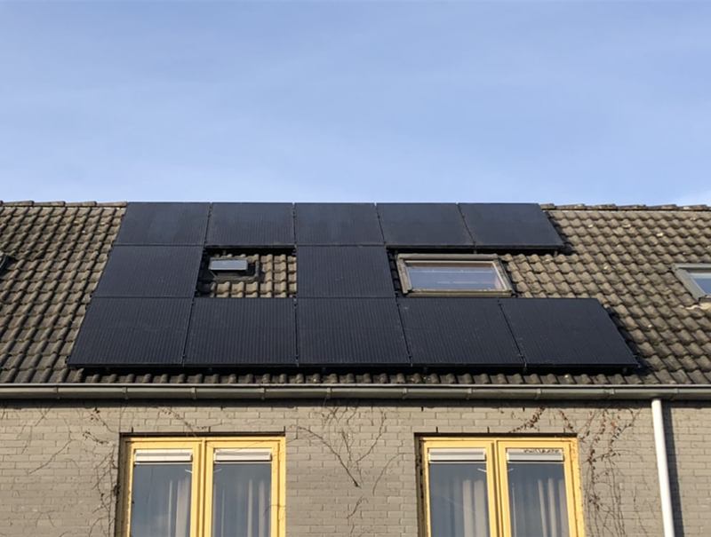 Zwarte zonnepanelen rondom dakramen op een pannendak